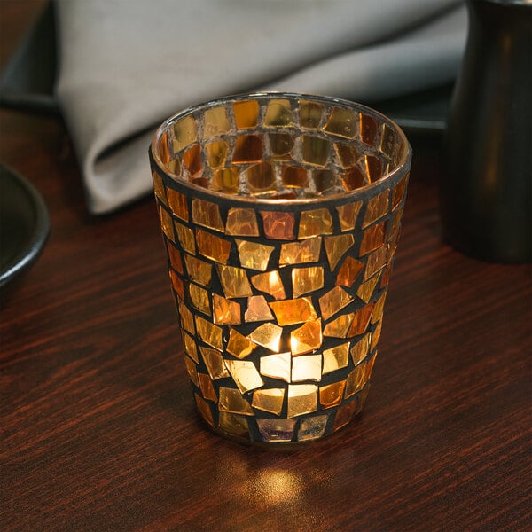 A Sterno Fall Mosaic candle holder with a lit candle on a table in an Asian cuisine restaurant.