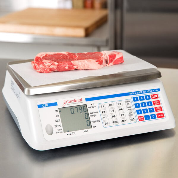 A Cardinal Detecto digital counting scale on a counter with a piece of raw meat.