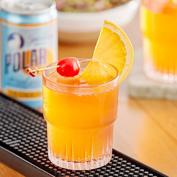 A glass of Polar orange drink with a cherry and a slice of orange on top.