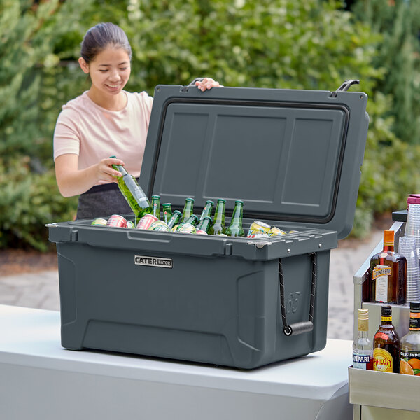 A woman putting bottles into a CaterGator outdoor cooler.