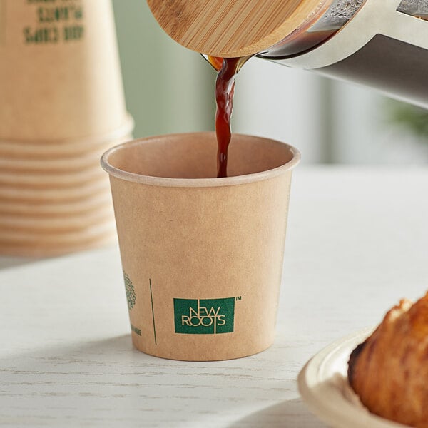 A close up of New Roots Smooth Single Wall Kraft paper cup of coffee being poured.