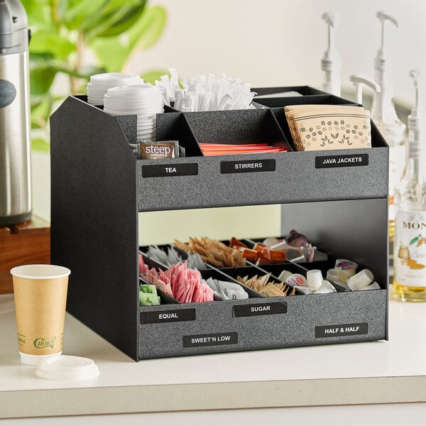 A black ServSense countertop condiment organizer with a variety of condiments inside.