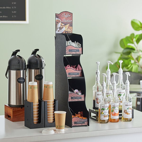 A ServSense black 8-section vertical countertop condiment organizer on a coffee shop counter with condiments and condiment bottles.