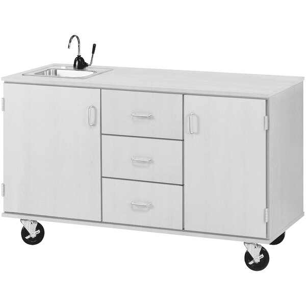 A white demonstration station with sink, drawers, and storage cabinets.