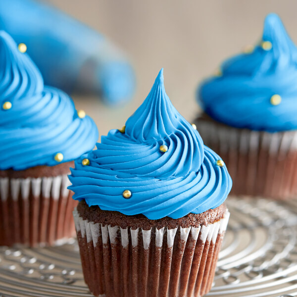 Three cupcakes with blue frosting on a silver plate.