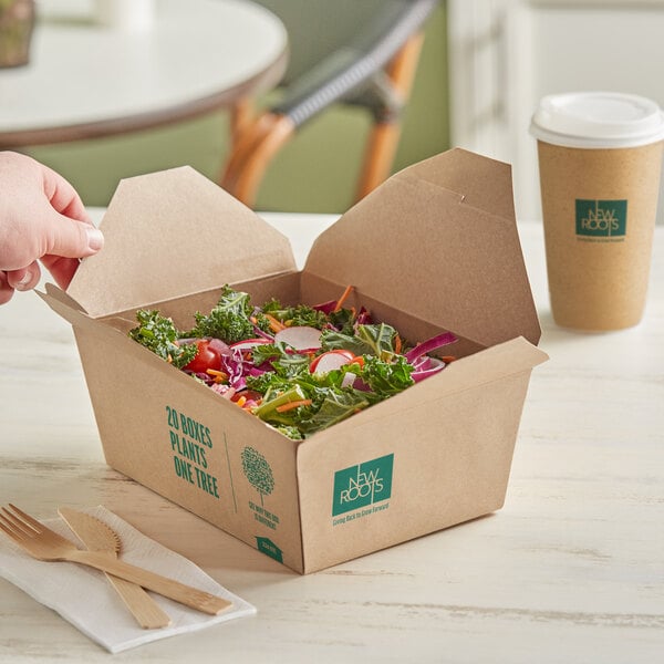 A hand holding a New Roots Kraft PLA-Lined Compostable #4 Take-Out Container filled with salad on a table.