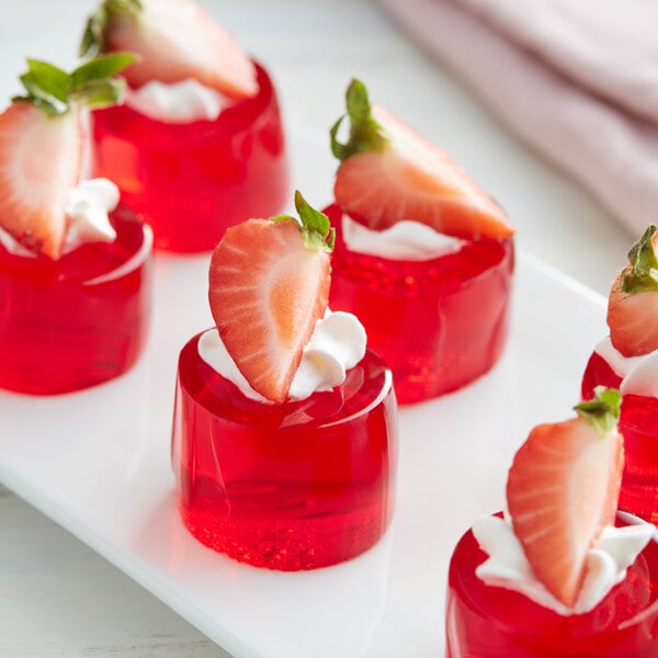 A plate of strawberry jello with strawberries on top.