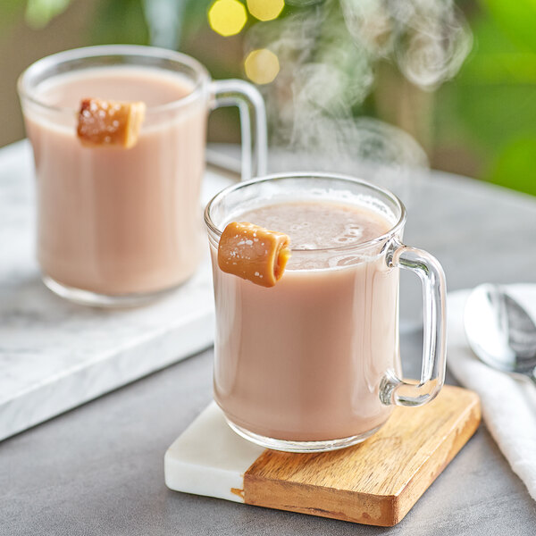A glass mug of UPOURIA salted caramel hot chocolate with salted caramel on top.