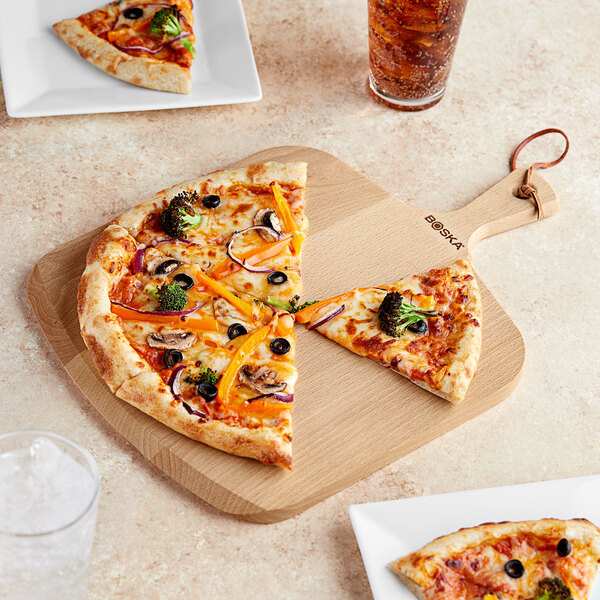 A pizza on a Boska beech wood serving board with a slice missing.