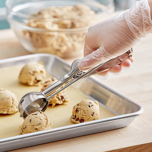 A person using a Choice #30 stainless steel ice cream scoop to scoop ice cream.