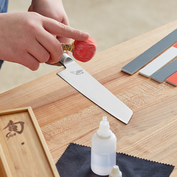 A person using a Shun knife to cut colorful paper.