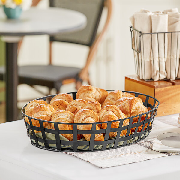 A black iron powder-coated oval basket filled with pastries on a table in a bakery display.