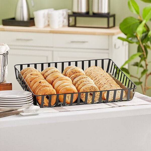 A black iron powder-coated rectangular basket filled with sliced bread on a counter.