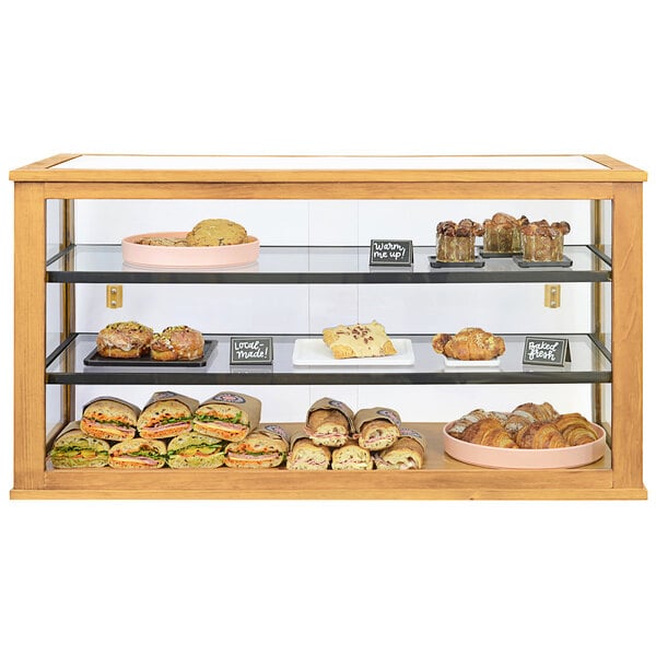 A Cal-Mil 3-tier bakery display case filled with pastries on a counter.