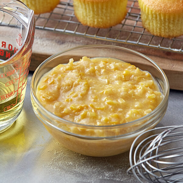 A bowl of corn pudding next to a measuring cup.