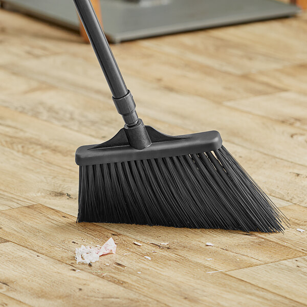 A black Lavex angled broom head on a wooden floor.