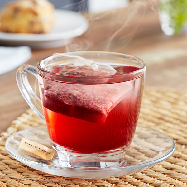 A glass cup of Bigelow Benefits Blueberry and Aloe Herbal Tea with a tea bag in it.