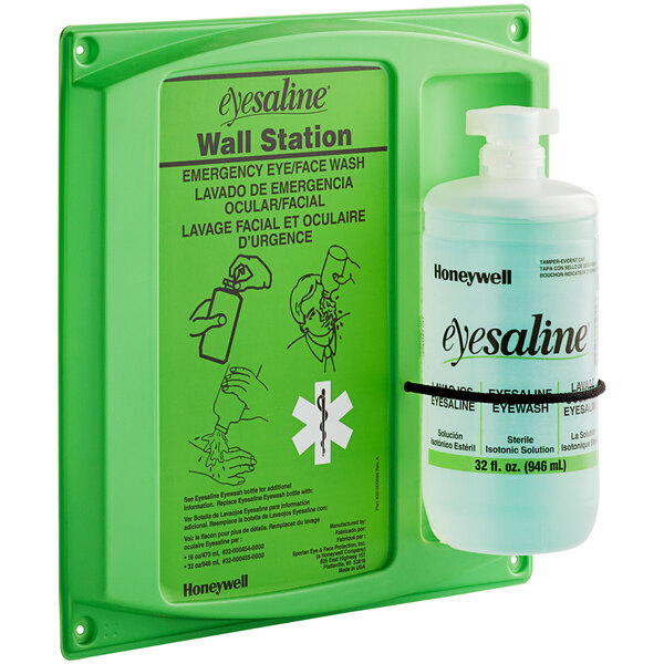 A Honeywell green wall station with a bottle of eye wash.