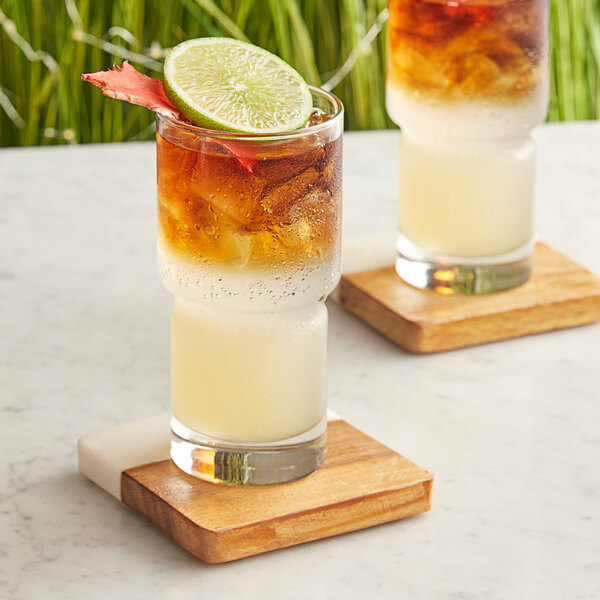 Two glasses of Top Hat Provisions Spicy Ginger Beer with lime on a wooden tray.