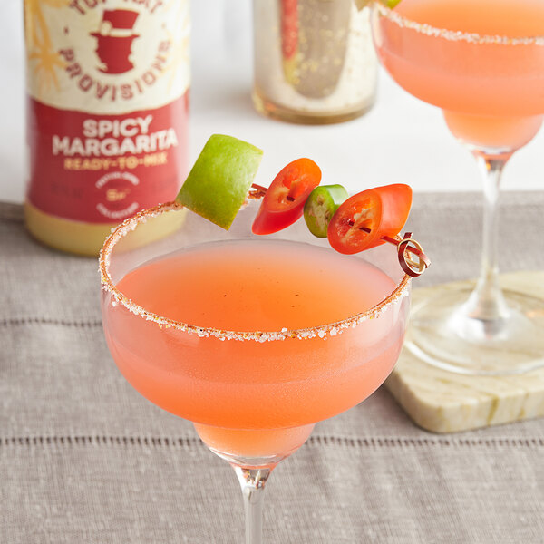 A glass with a Top Hat Provisions Spicy Margarita garnished with a slice of tomato.