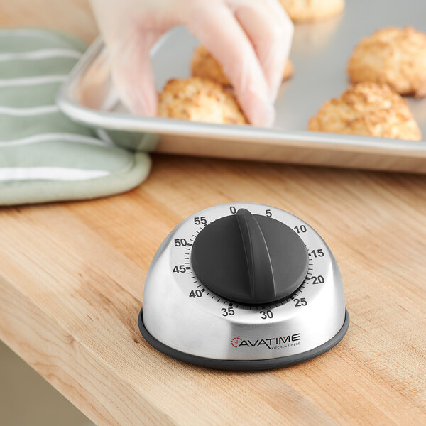 A person using an AvaTime stainless steel mechanical kitchen timer to bake cookies.