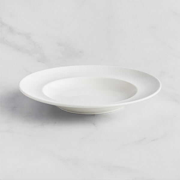 A RAK Porcelain ivory deep plate with an embossed wide rim on a white surface.