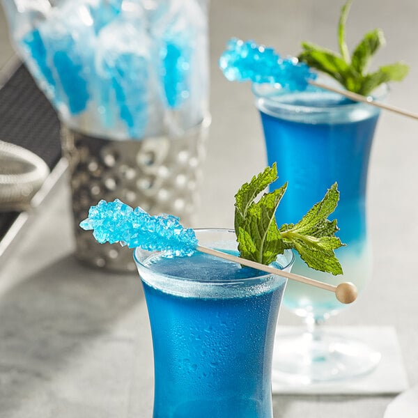A blue drink with a Roses Dryden and Palmer Blue Raspberry rock candy swizzle stick on top.