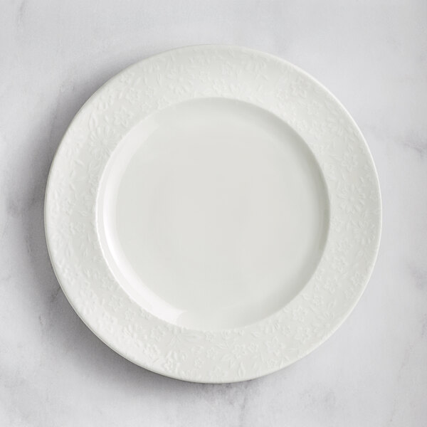 A RAK Porcelain ivory flat plate with an embossed floral pattern on the rim.