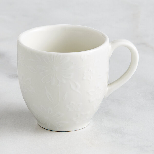 A white RAK Porcelain espresso cup with an ivory floral design and handle.