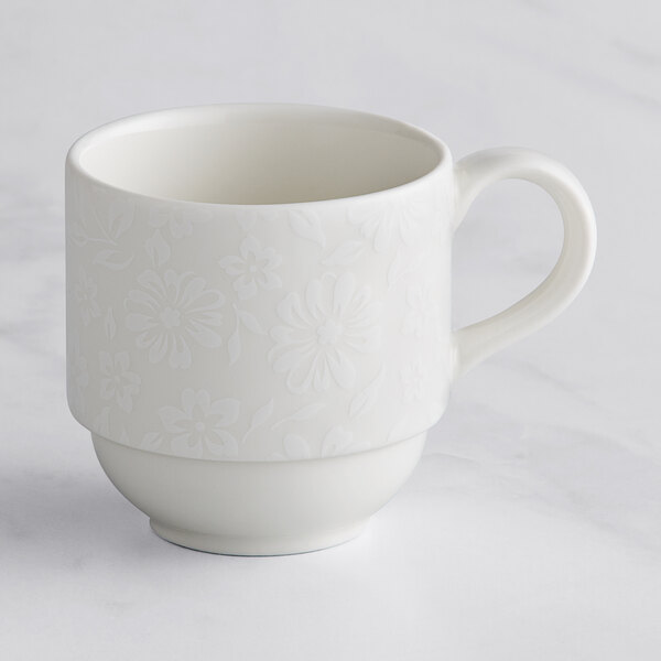 A white RAK Porcelain stackable cup with an ivory floral design and handle.
