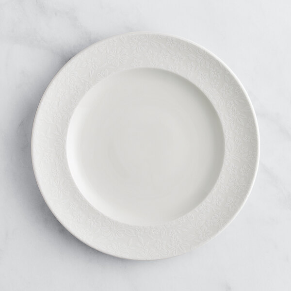 A RAK Porcelain ivory flat plate with a floral design on a white surface.