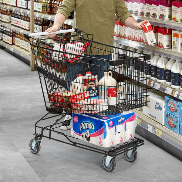 A man pushing a black Regency Supermarket shopping cart filled with groceries.