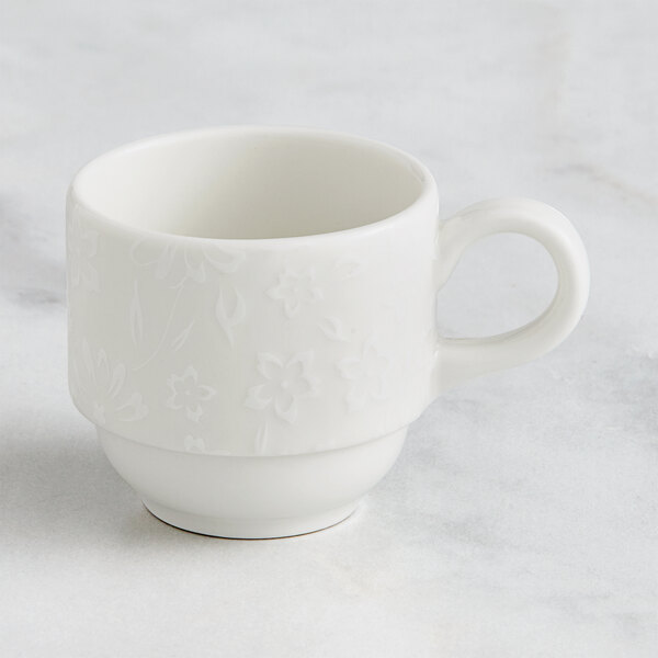 A white RAK Porcelain espresso cup with an embossed flower design and a handle.