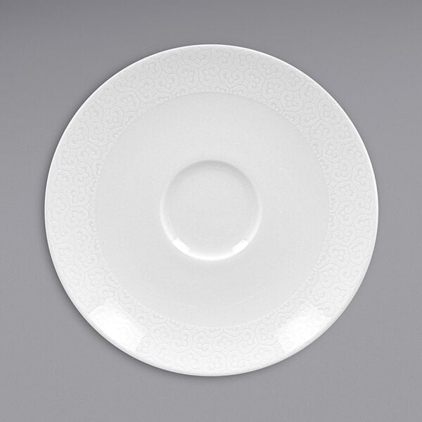 A white RAK Porcelain saucer with a circular edge and embossed pattern.