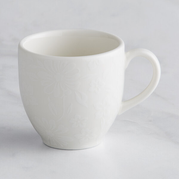 A close up of a white RAK Porcelain espresso cup with an ivory floral design.