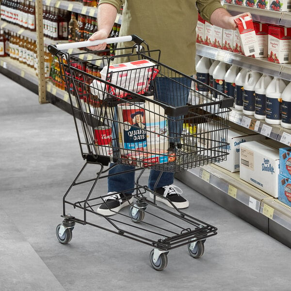 A man pushing a Regency Supermarket black shopping cart in a grocery store aisle.