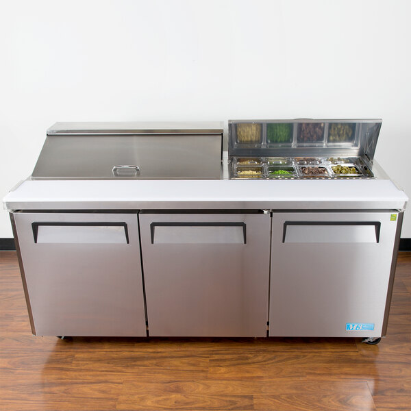 A Turbo Air refrigerated sandwich prep table with a stainless steel counter top and three doors.