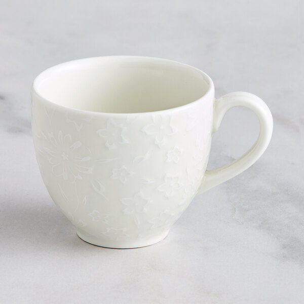 A white RAK Porcelain coffee cup with an embossed floral design.