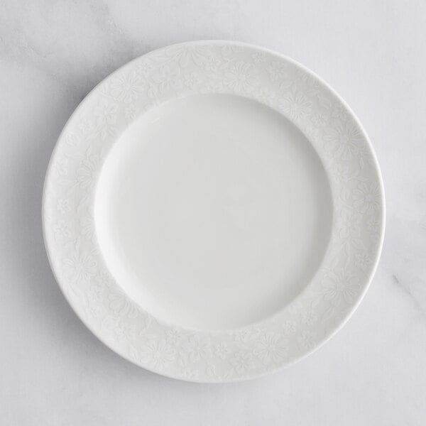 A white RAK Porcelain flat plate with an ivory floral pattern on the rim.