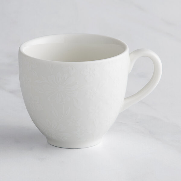 A white RAK Porcelain cup with an embossed floral design.