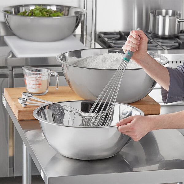 A woman mixing flour in a Choice XL stainless steel mixing bowl.