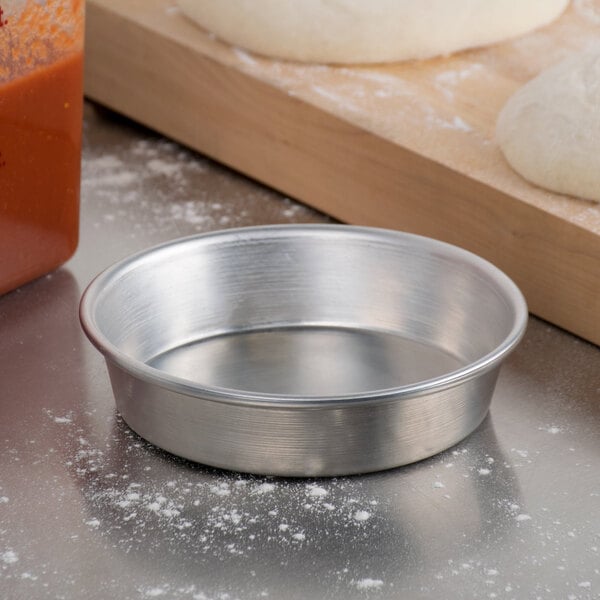 An American Metalcraft heavy weight aluminum pizza pan with dough in it.