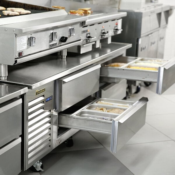 The Traulsen refrigerated chef base in a stainless steel kitchen with a large oven.