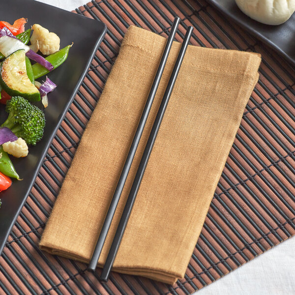 A plate of vegetables and Emperor's Select black melamine chopsticks on a place mat.