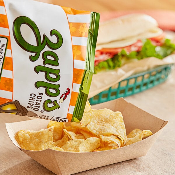 A paper bowl of Zapp's Hotter 'N Hot Jalapeno Potato Chips on a table with a sandwich.