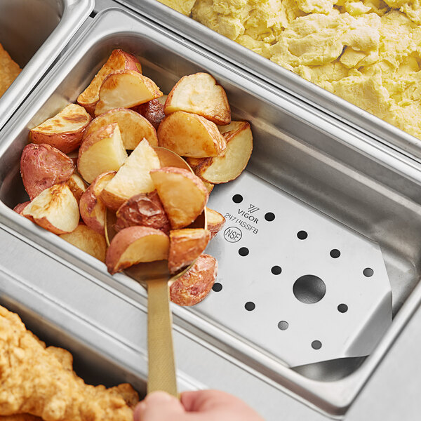 A Vigor stainless steel false bottom in a tray of food with a potato wedge.