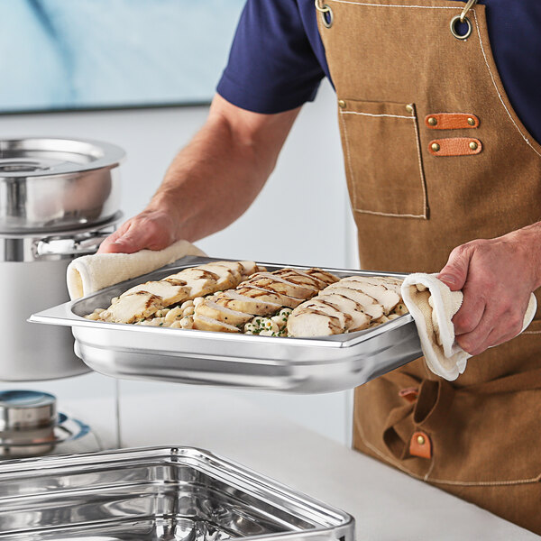 A person holding a tray of food using an Acopa Voyage square chafer pan.