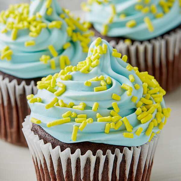 A close up of a cupcake with blue frosting and yellow sprinkles.