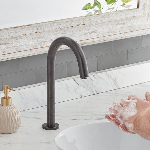 A person using a Waterloo hands-free sensor faucet to wash their hands under a sink.