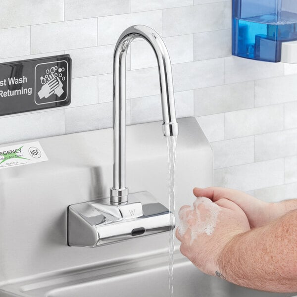 A person washing their hands under a Waterloo hands-free faucet.